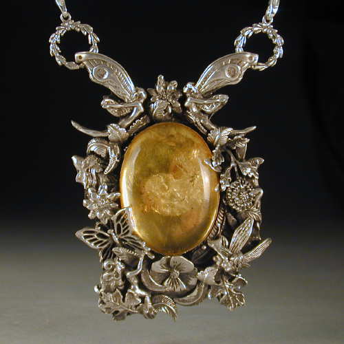 Six fairies play in the leaves and flowers around this beautiful piece of amber.